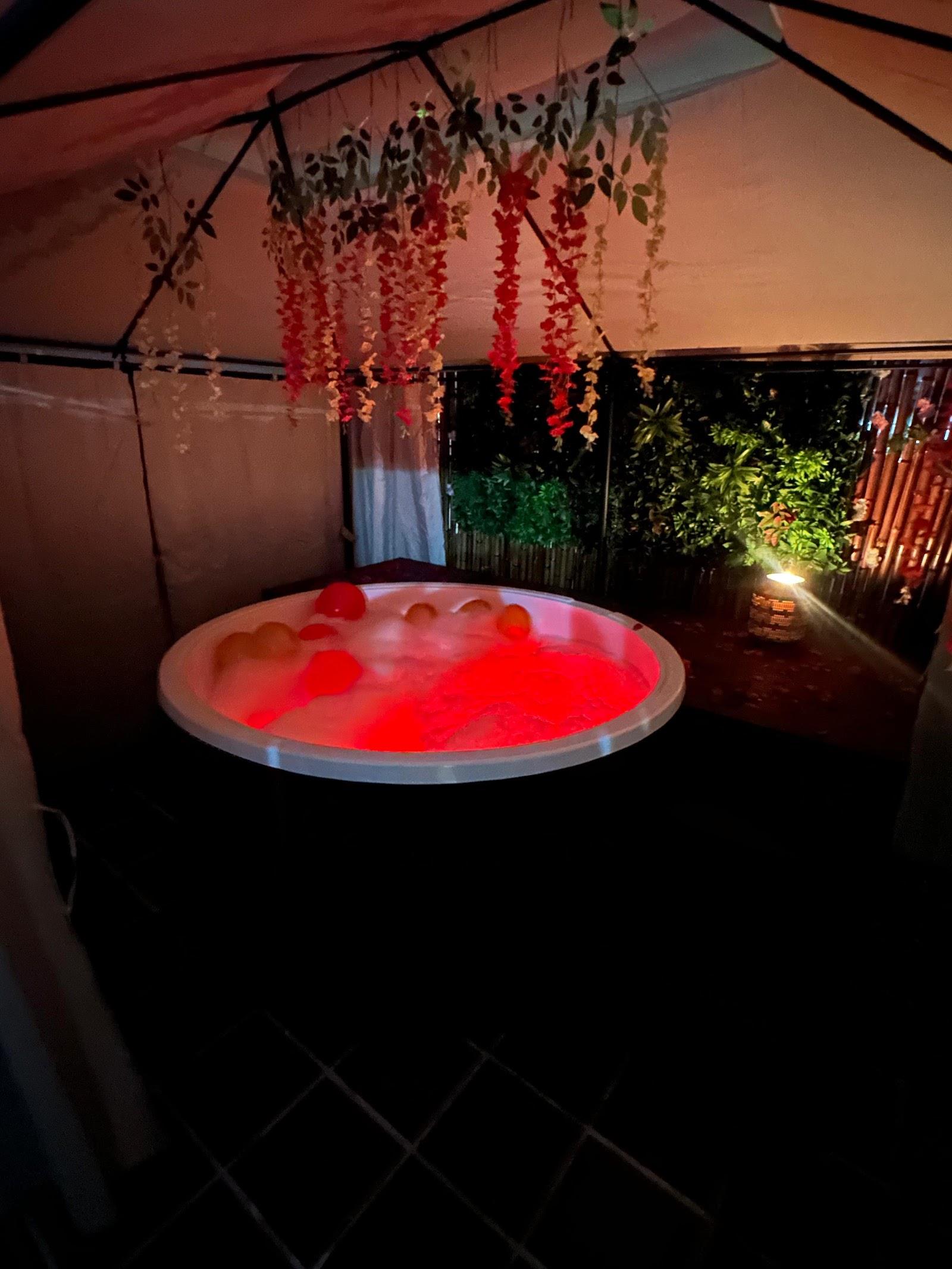 Jacuzzi iluminado de noche entre plantas y bambú