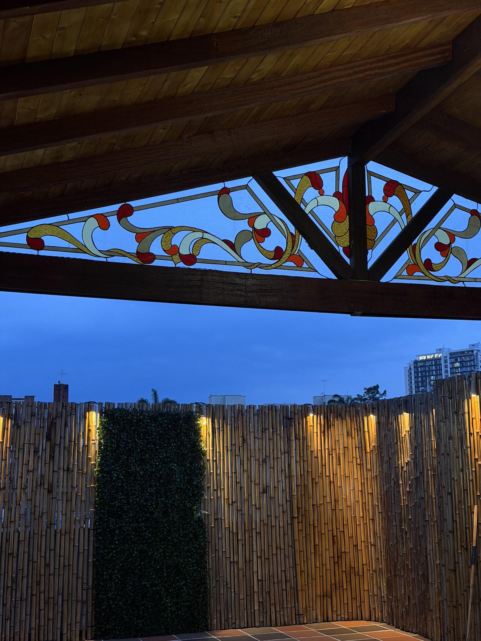 Techo de madera con vitral de flores rojas y ámbar sobre la terraza de bambú